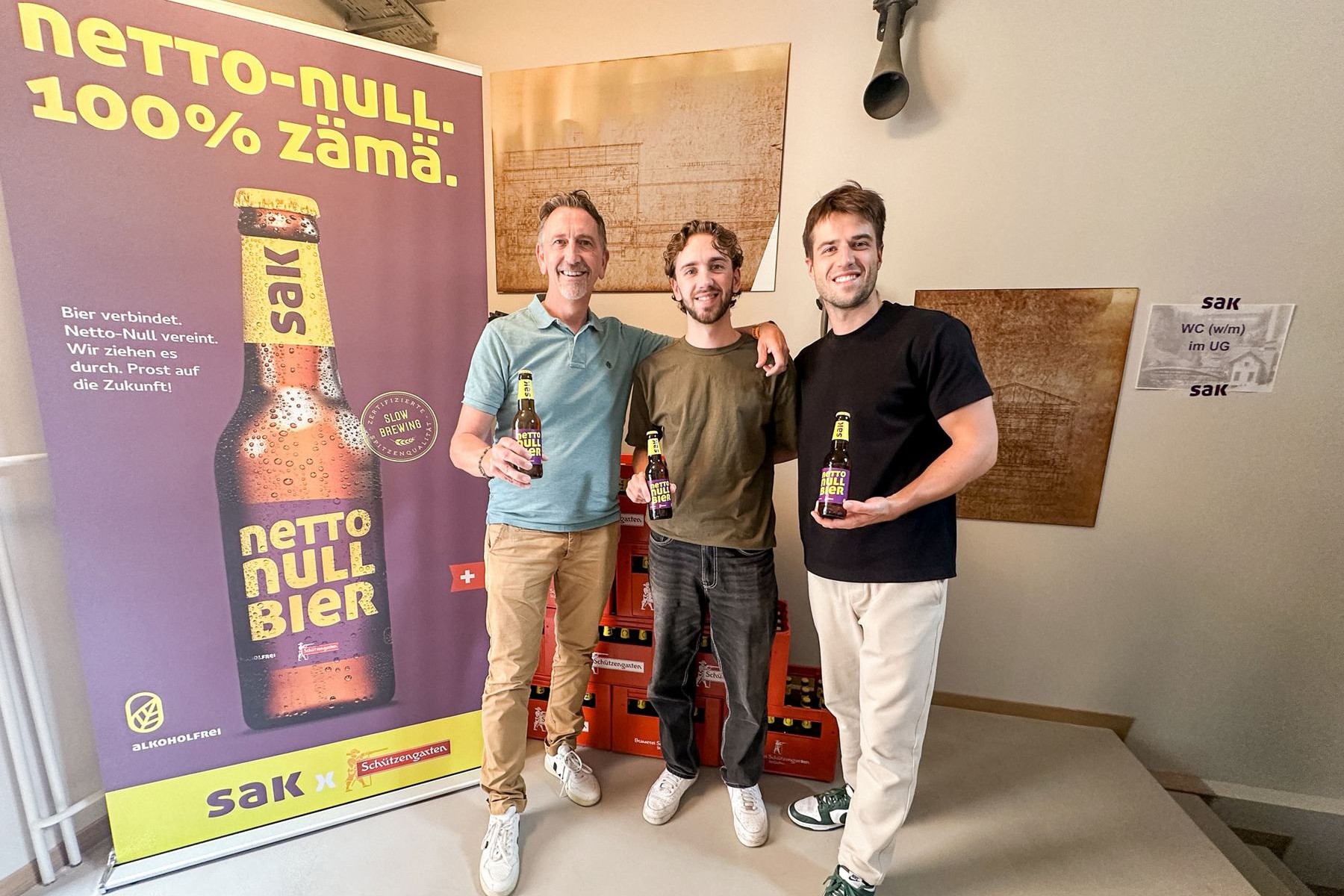 Netto Null Bier: Team vor dem Plakat «Netto-Null. 100% zäme»