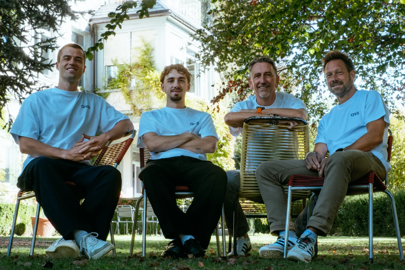 Das Divid-Team mit Tobias Krüsi, Nico Krüsi, Adi Krüsi und Marco Hobi (von links) sitzt in weissen Divid-Shirts im Garten vor einem Altbau in St. Gallen