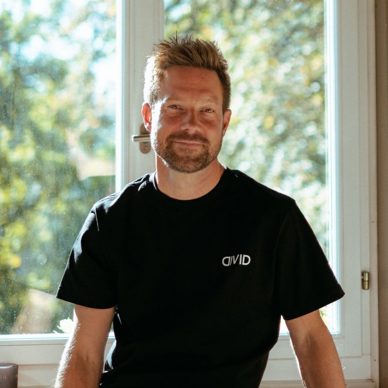 Marco Hobi, Operations Lead bei Divid in St. Gallen, sitzt vor einem Fenster mit Bäumen im Hintergrund